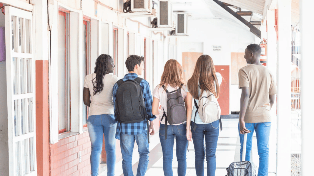 diverse group of students walking down a hallway together happily. 