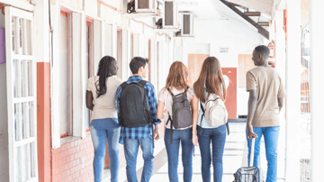 diverse group of students walking down a hallway together happily. 