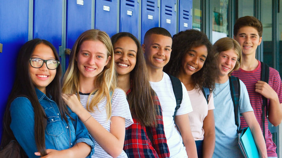 Diverse group of happy students infront of their lockers. 