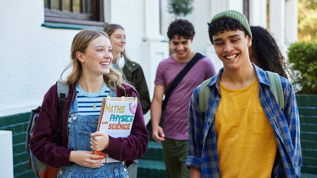 A group of diverse teenagers walking outside and smiling together, demonstrating healthy screen time balance and positive youth wellness habits.
