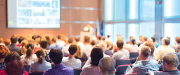 Attendees listening to a presenter at a conference.