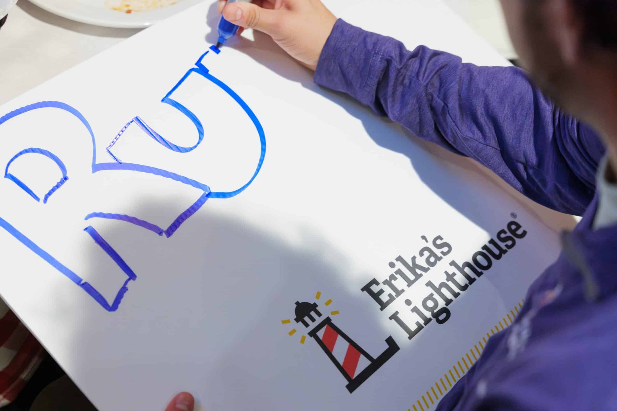 hand writing a sign with a blue marker